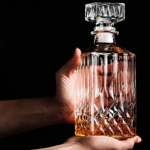 Carafe à whisky design présenté par deux main sur un fond noir