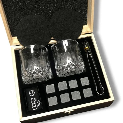 Coffret en bois contenant deux verres texturés, des pierres réfrigérantes, des sous-verres et des pinces dorées, idéal pour les amateurs de whisky.