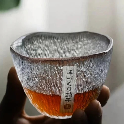 Ce verre à whisky texturé, tenu dans la main, illustre à la fois simplicité et élégance artisanale.