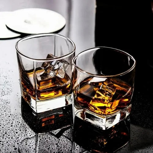 Deux verres carrés sur une table humide, reflétant le contraste entre modernité et convivialité.