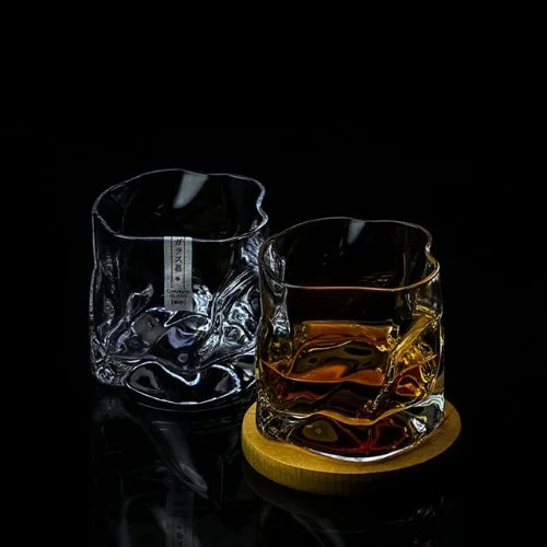 Deux verres à whisky design, l’un vide et l’autre garni, posés sur un socle en bois, offrant une expérience visuelle unique.