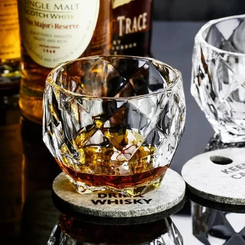 Verre à whisky sur un dessous de verre avec en fond des bouteilles de Whisky
