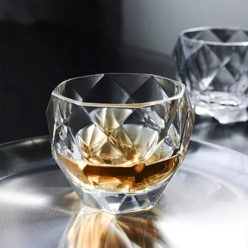 Le verre à whisky diamant au centre de la scène, entouré de bouteilles de spiritueux prestigieux pour une dégustation haut de gamme.