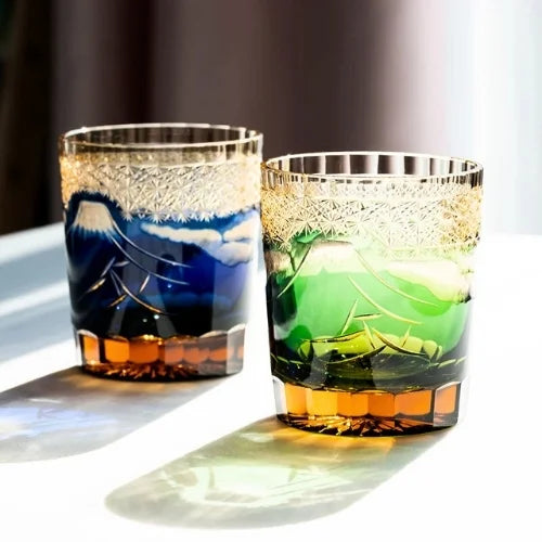 Deux verres gravés, l'un bleu et l'autre vert, capturant la lumière pour une expérience visuelle unique.