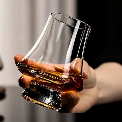 Un verre à whisky irlandais incliné dans une main, mettant en lumière sa conception ergonomique et raffinée.