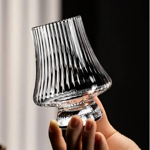 Un verre à whisky irlandais texturé, tenu en main, révélant une forme élégante et unique.