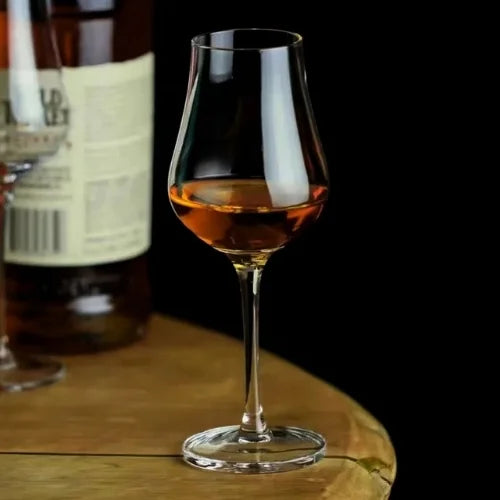 Un verre tulipe rempli de whisky doré, posé sur une table, illustrant une élégance intemporelle.