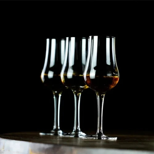 Un verre tulipe rempli de whisky doré, posé sur une table, illustrant une élégance intemporelle.