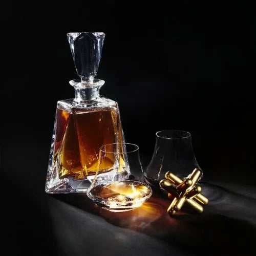 Carafe en cristal remplie de whisky, accompagnée de verres de dégustation et d'accessoires dorés sur fond noir élégant.