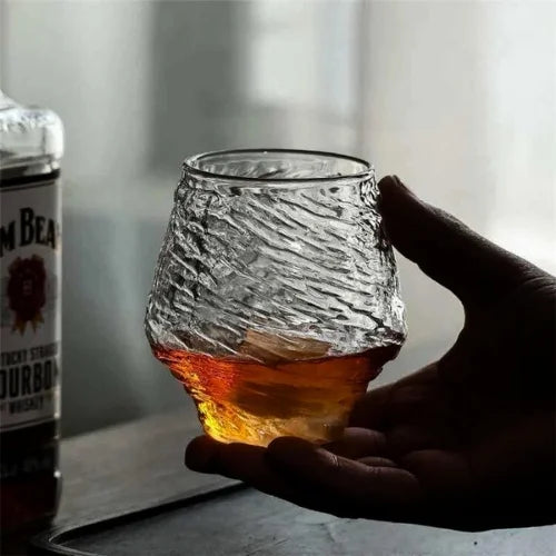 Le verre à whisky japonais tenu dans la main, mettant en avant sa texture irrégulière et son design inspiré de la nature.