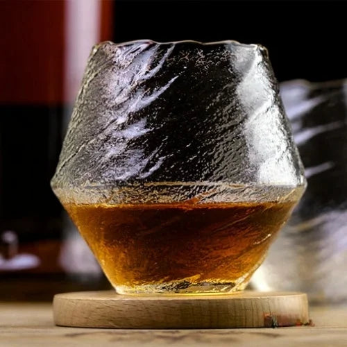 Un verre japonais rempli d’un whisky ambré, posé sur un socle en bois, ajoutant une touche naturelle et sophistiquée.