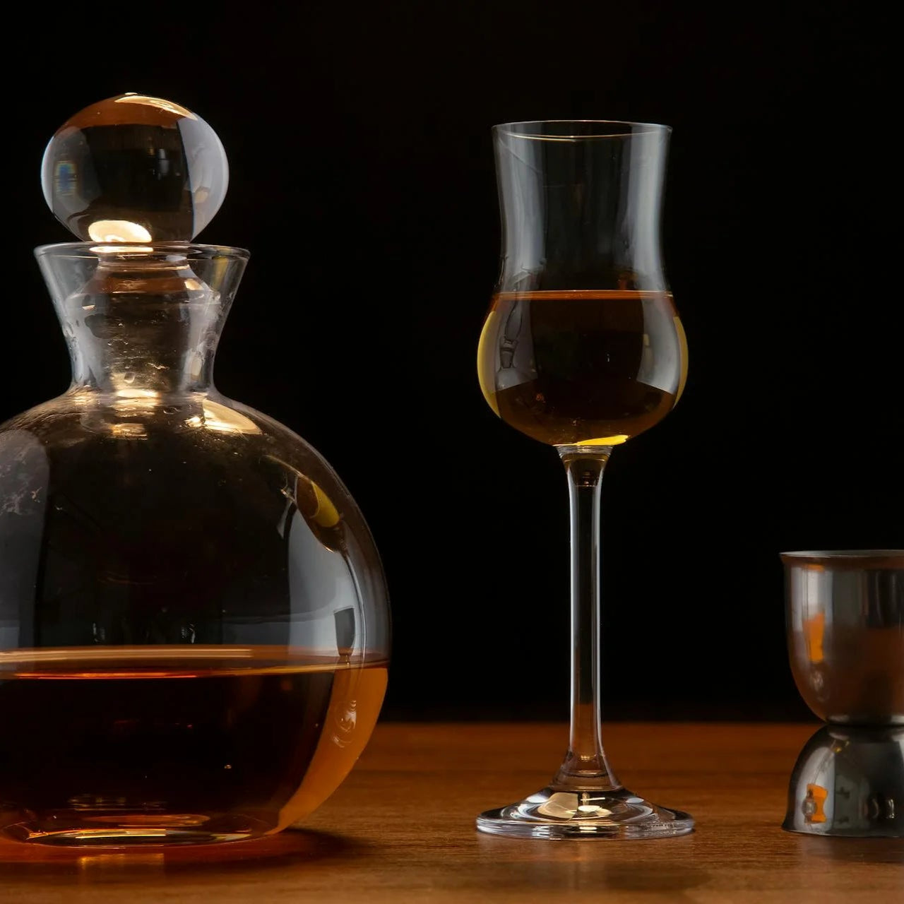 Une carafe et un verre à whisky accompagné de leur doseur, posé sur un table